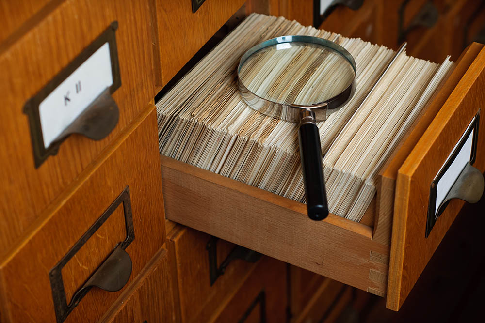 A magnifying glass sits on top of library records.