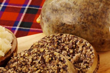 Haggis and neeps and tatties and whisky on a tartan tablecloth.